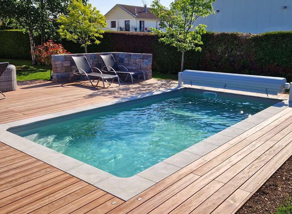 Piscine en béton armé avec terrasse bois et volet roulant