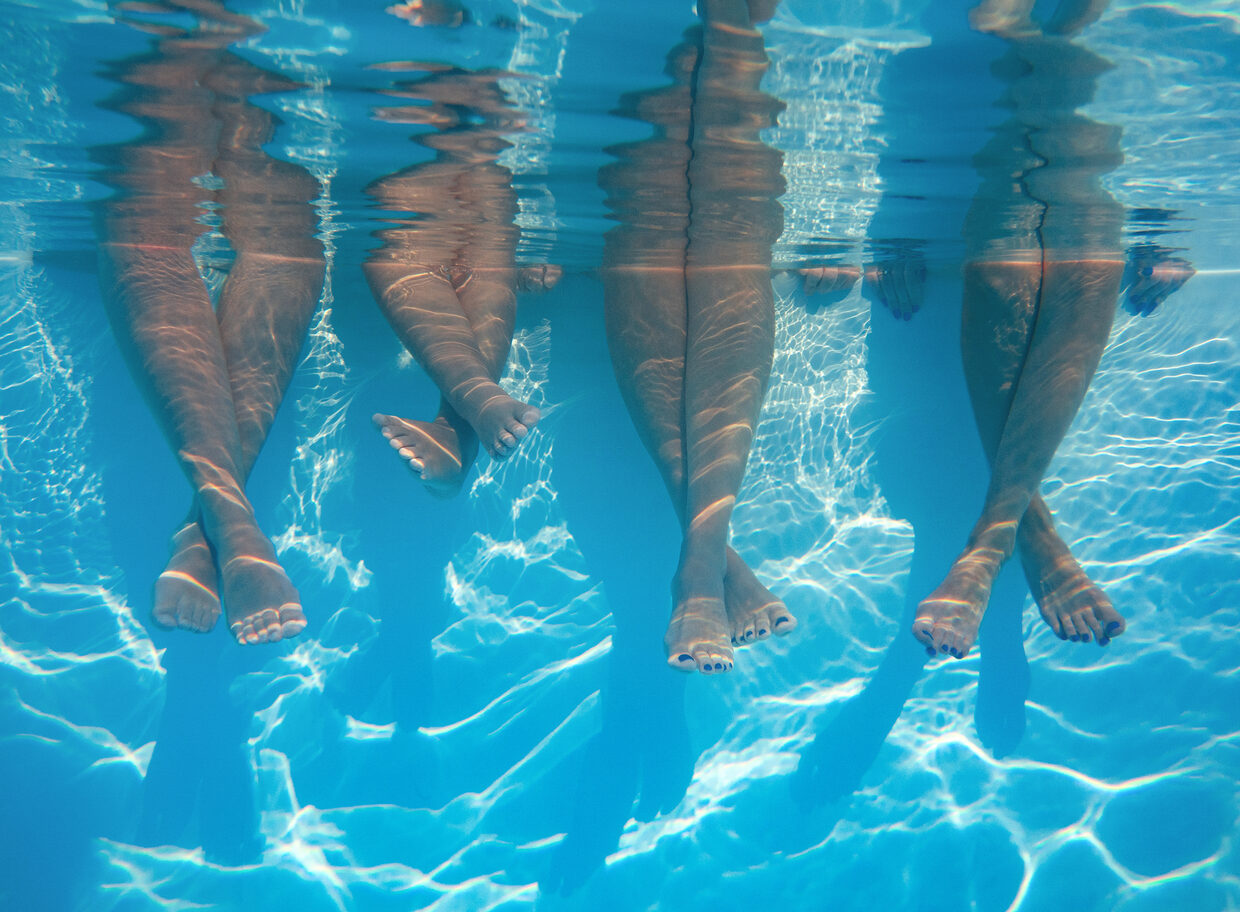 Baigneurs assis au bord d'une piscine, jambes dans l'eau